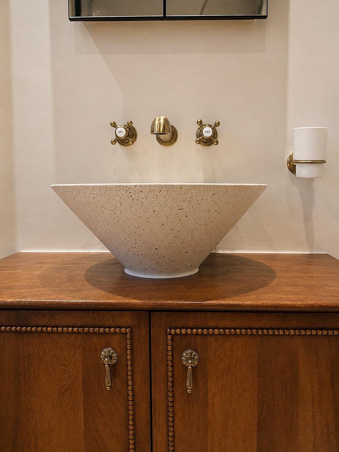 Stone basin on a timber vanity with wall-mounted antique brass taps