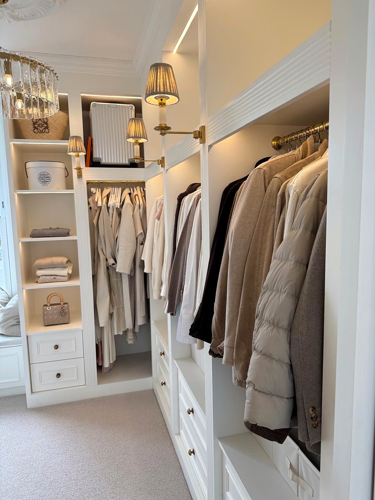 Walk-in wardrobe with fitted joinery, brass rails and lit shelves