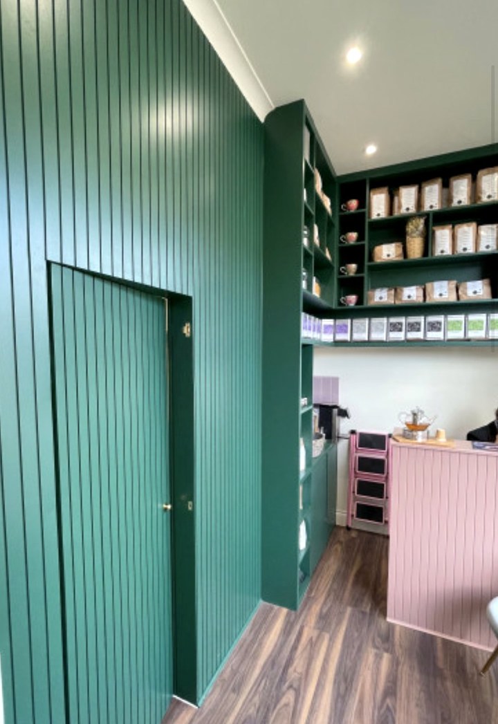 Green fluted wall panelling with a concealed door and tea shelving beyond