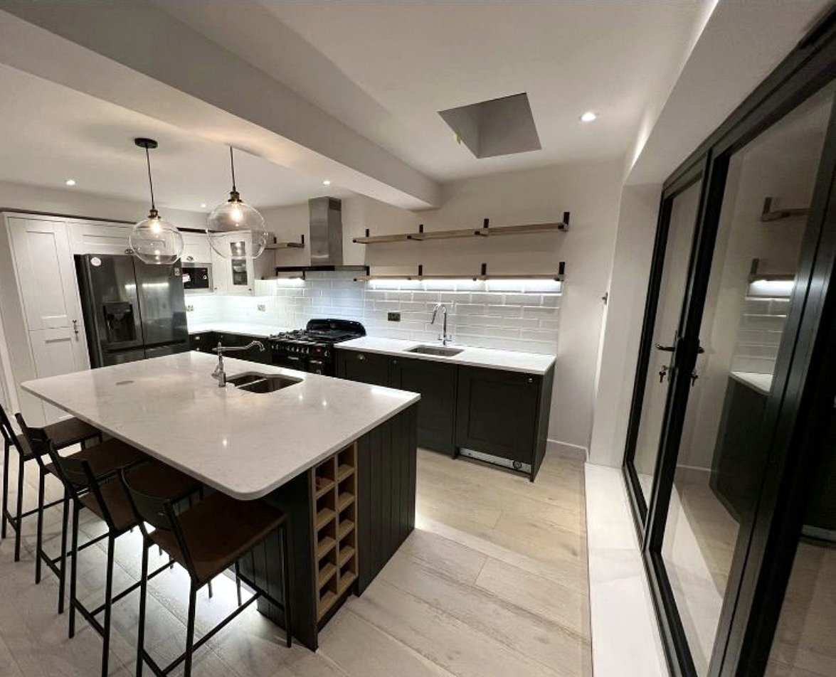 The whole kitchen: island with seating and wine rack, open shelves and bifold doors